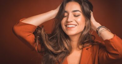 smiling woman in brown top holding hairs